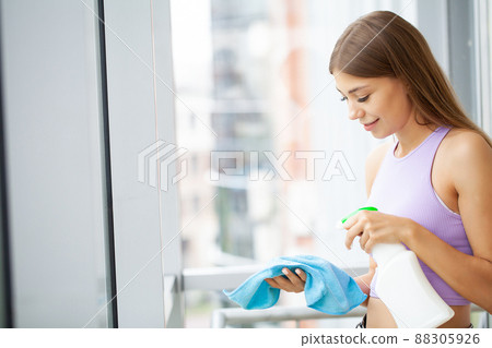 Happy young woman housewife washes a window 88305926