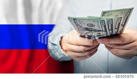 Russian flag and US dollars in hands. Business, tax, banking and finance concept Russian flag and US dollars in hands. Business, tax, banking and finance concept 88305970