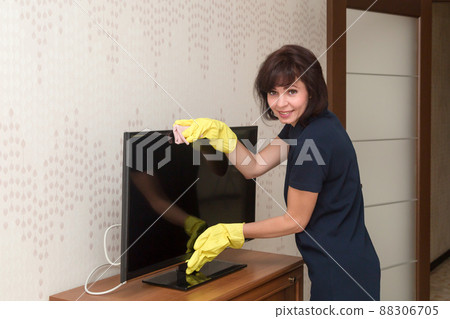 Wife dusting TV screen while cleaning house Wife dusting TV screen while cleaning house 88306705