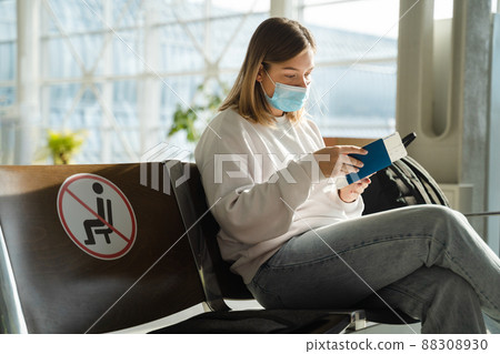 Woman sitting in airport lounge and looking at her passport 88308930
