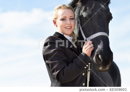 The bond between rider and horse. Low angle portrait of a young female rider hugging her horse affectionately. The bond between rider and horse. Low angle portrait of a young female rider hugging her horse affectionately. 88309601