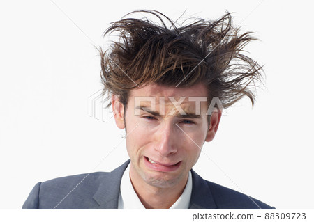 I need help. A young businessman with messy hair whimpering while isolated on white. 88309723