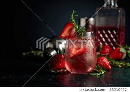 Cocktail with ice, strawberries, and rosemary. 88310432