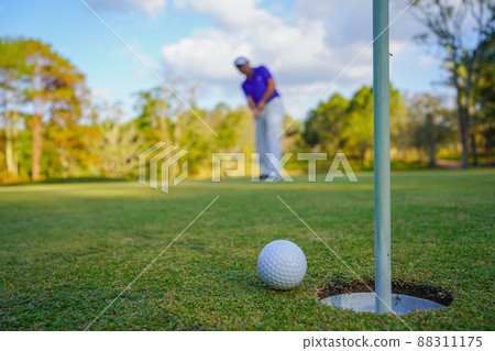 Golfer action to win after long putting golf ball on the green golf, lens flare on sun set evening time. 88311175