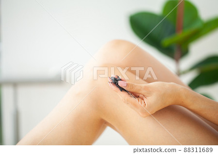 Woman cleans skin of the body with coffee scrub in bathroom. Woman cleans skin of the body with coffee scrub in bathroom. 88311689