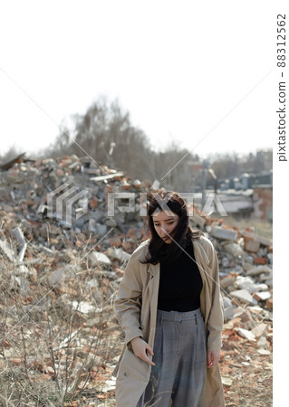A lonely girl in a coat and jeans on the ruins of a ruined house. consequences of the war grain effect A lonely girl in a coat and jeans on the ruins of a ruined house. consequences of the war grain effect 88312562