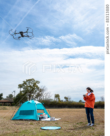 Young woman enjoying drone aerial photography at a campsite Young woman enjoying drone aerial photography at a campsite 88313880