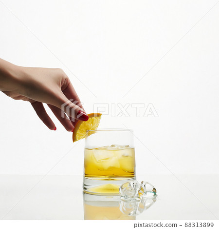 Female Hand put orange on glass with Ice and fresh juice Female Hand put orange on glass with Ice and fresh juice 88313899