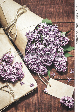 Gift and bouquet of lilacs on a wooden table 88315048