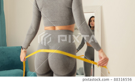 Fitness Woman Measuring butt With Tape at home. strong buttocks concept. 88316556