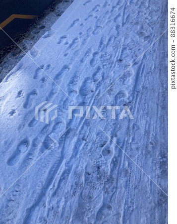 It is a human footprint that remains in the snow that has fallen on the road. 88316674