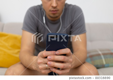young man in headphones watching at mobile phone young man in headphones watching at mobile phone 88316690
