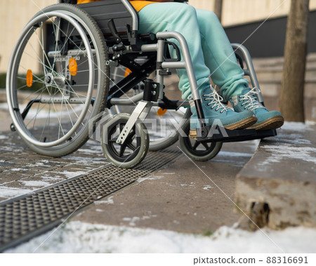 Woman in a wheelchair near the stairs in the park in winter. 88316691