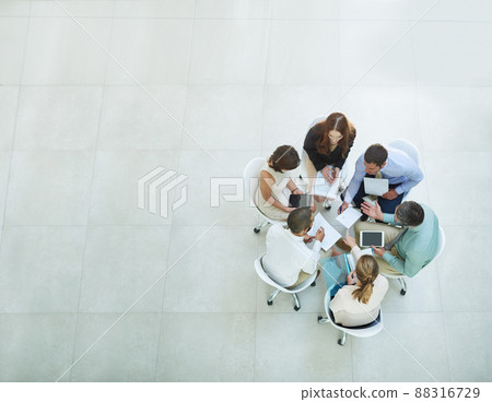 Putting their heads together. High angle shot of a group of businesspeople meeting in the office. 88316729