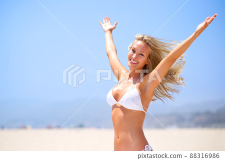 Loving the summer sun and feeling amazing. A beautiful young woman with her arms outstretched at the beach. Loving the summer sun and feeling amazing. A beautiful young woman with her arms outstretched at the beach. 88316986