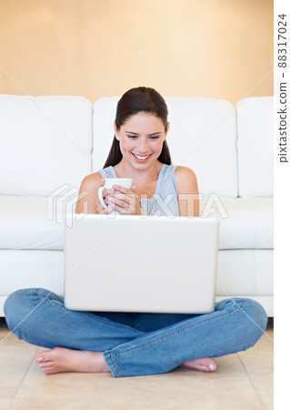 Coffee and a bit of social networking. A thoughtful young beauty with a laptop in her lap enjoying a cup of coffee. 88317024