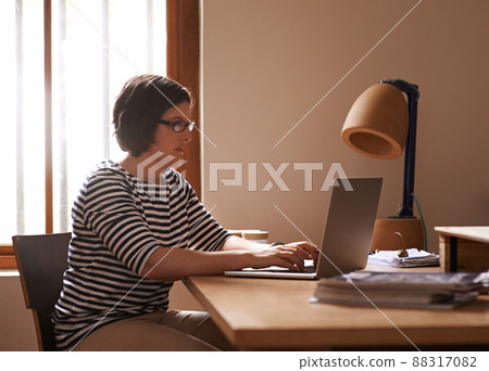 Morning admin. A cropped shot of a woman sitting at a desk in her home and working on a laptop. Morning admin. A cropped shot of a woman sitting at a desk in her home and working on a laptop. 88317082