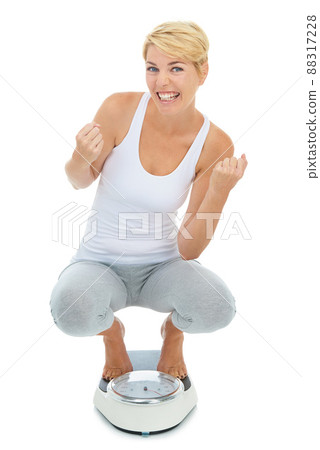 Yes Ive reached my target weight. A young blond woman standing on a scale with her arms raised in celebration. Yes Ive reached my target weight. A young blond woman standing on a scale with her arms raised in celebration. 88317228