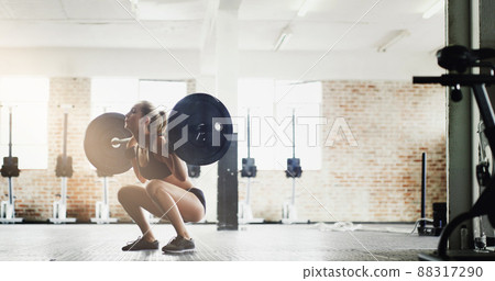 Stay sexy, squat often. Full length shot of an attractive young woman lifting weights in the gym. Stay sexy, squat often. Full length shot of an attractive young woman lifting weights in the gym. 88317290