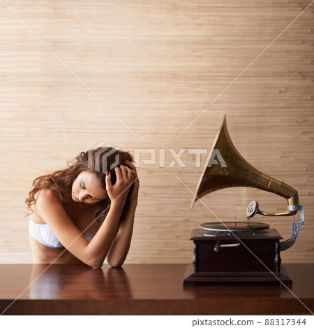 Music to suit the mood. An attractive young woman in lacy lingerie sitting beside a gramophone. 88317344