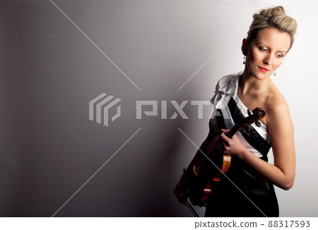 Feeling the heart and soul of music. Studio shot of a beautiful young woman holding a violin. Feeling the heart and soul of music. Studio shot of a beautiful young woman holding a violin. 88317593