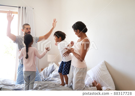 The fun never stops in our house. Shot of a beautiful young family of four having fun and spending time together in their bedroom at home. 88317728