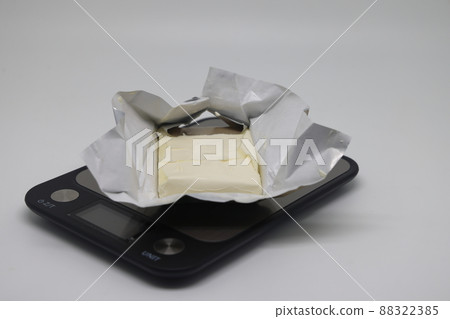A piece of butter in a package on a white background, proper nutrition, calorie counting A piece of butter in a package on a white background, proper nutrition, calorie counting 88322385