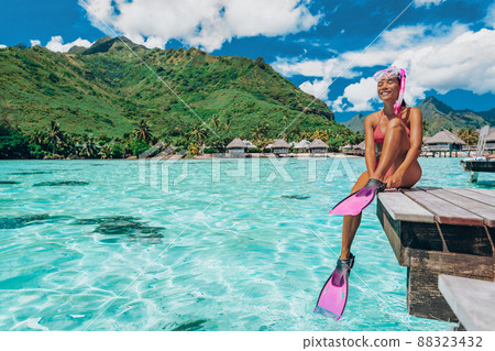 Beach Luxury Travel Vacation in Tahiti. Snorkel swim woman going snorkeling in coral reefs of French Polynesia ocean in overwater bungalow resort with snorkelling mask, fins. Christmas winter getaway Beach Luxury Travel Vacation in Tahiti. Snorkel swim woman going snorkeling in coral reefs of French Polynesia ocean in overwater bungalow resort with snorkelling mask, fins. Christmas winter getaway 88323432
