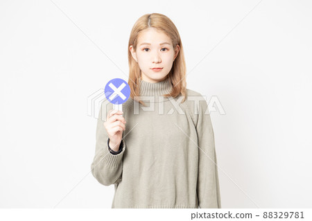 Young woman standing in front of white background showing NG placard Young woman standing in front of white background showing NG placard 88329781