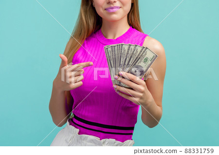 woman in a pink shirt points a finger at money dollars on a blue background woman in a pink shirt points a finger at money dollars on a blue background 88331759