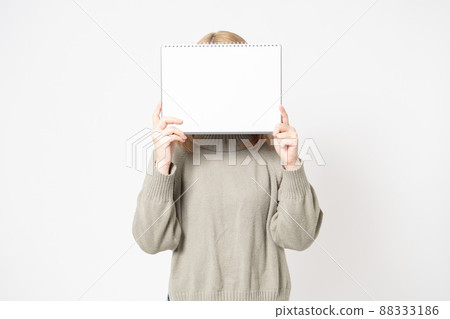 Young woman standing in front of white background showing a small sketchbook Young woman standing in front of white background showing a small sketchbook 88333186