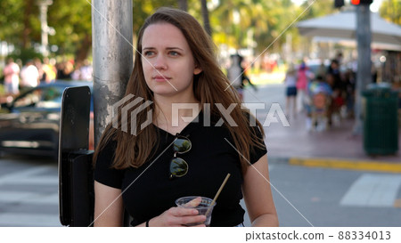 Young pretty woman has a cold drink in the sun of Miami Beach 88334013