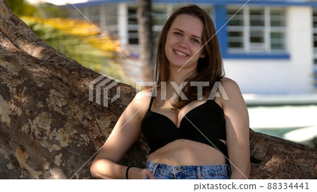 Young sexy woman leaning against a palm tree at the beach 88334441