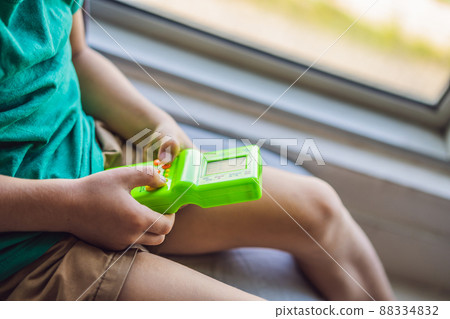 Young boy playing old school portable game console, electronic retro pocket toy with monochrome display Young boy playing old school portable game console, electronic retro pocket toy with monochrome display 88334832