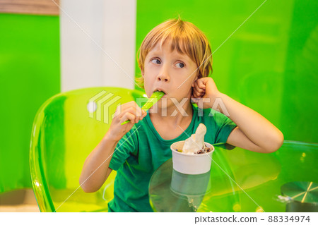 Happy young boy eating a tasty ice cream or frozen yogurt 88334974