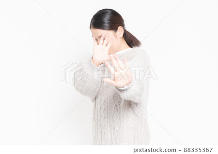 Woman standing in front of white background and making NG gestures 88335367