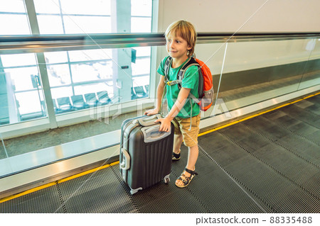 Funny little boy going on vacations trip with suitcase at airport, indoors Funny little boy going on vacations trip with suitcase at airport, indoors 88335488