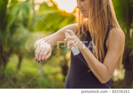 Woman spraying insect repellent on skin outdoor 88336261