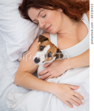 Caucasian woman is napping in bed hugging her beloved dog. Caucasian woman is napping in bed hugging her beloved dog. 88336433