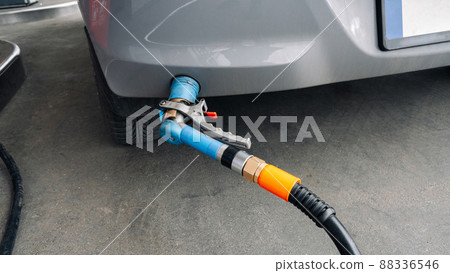 Gas station. Pump fuel petrol in tank car. Gasoline oil in nozzle. Close-up of the hand and the fuel gun. Blurred background. 88336546