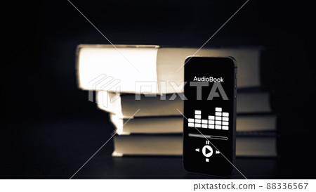 Audiobook education. Smartphone screen with audiobook application on paper books black background. Ebook e learning electronic internet mobility concept. Audiobook education. Smartphone screen with audiobook application on paper books black background. Ebook e learning electronic internet mobility concept. 88336567
