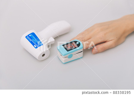 Pulse oximeter and thermometer gun on white background. Infrared isometric thermometer gun to check body temperature for virus symptoms. Measuring oxygen saturation, pulse rate and oxygen levels. Pulse oximeter and thermometer gun on white background. Infrared isometric thermometer gun to check body temperature for virus symptoms. Measuring oxygen saturation, pulse rate and oxygen levels. 88338195