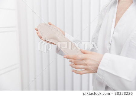Doctor holding orthopedic insoles in his hands. Orthopedist tests the medical device. Orthopedic insoles on a white. Foot care. Flat Feet Correction. Prevention of flat feet and foot diseases. 88338226