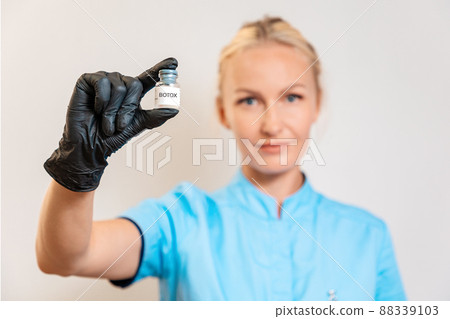 The portrait of the doctor of aesthetic medicine shows an ampoule with botulinum toxin. The concept of plastic surgery and professional cosmetology The portrait of the doctor of aesthetic medicine shows an ampoule with botulinum toxin. The concept of plastic surgery and professional cosmetology 88339103