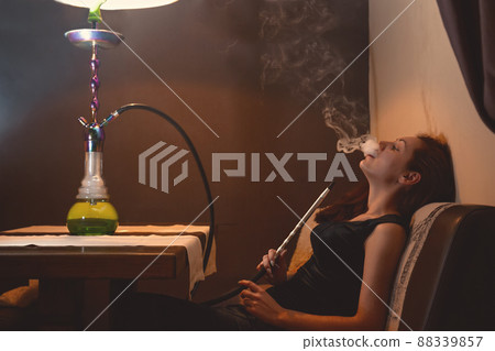 A young woman relaxing on the couch Smoking a hookah 88339857