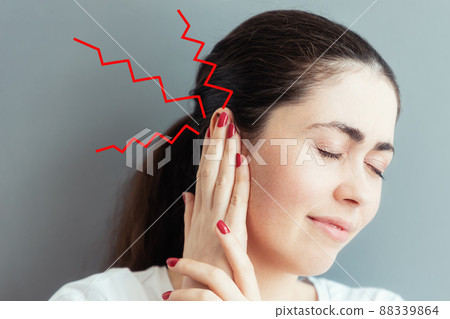 Portrait of a suffering young Caucasian woman covering her ear with her hands from pain or a loud sound. Gray background. The concept of deafness and ear diseases 88339864