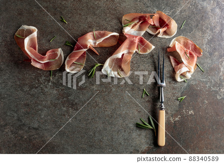 Prosciutto with rosemary on an old stone background. Prosciutto with rosemary on an old stone background. 88340589