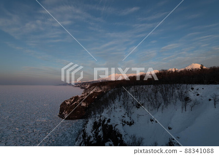 Shiretoko: The rock wall on the west coast of Shiretoko in the evening light, the Shiretoko mountain range, and the drift ice field 88341088