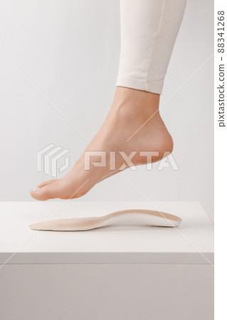 Medical insoles. Isolated orthopedic insoles on a white background. Treatment and prevention of flat feet and foot diseases. Foot care. Insole cutaway layers. Leg hanging over the insole. Medical insoles. Isolated orthopedic insoles on a white background. Treatment and prevention of flat feet and foot diseases. Foot care. Insole cutaway layers. Leg hanging over the insole. 88341268