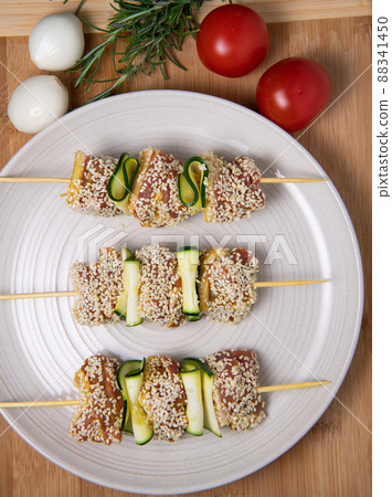 Raw lamb skewers with zucchini slices and sesame seeds Raw lamb skewers with zucchini slices and sesame seeds 88341450